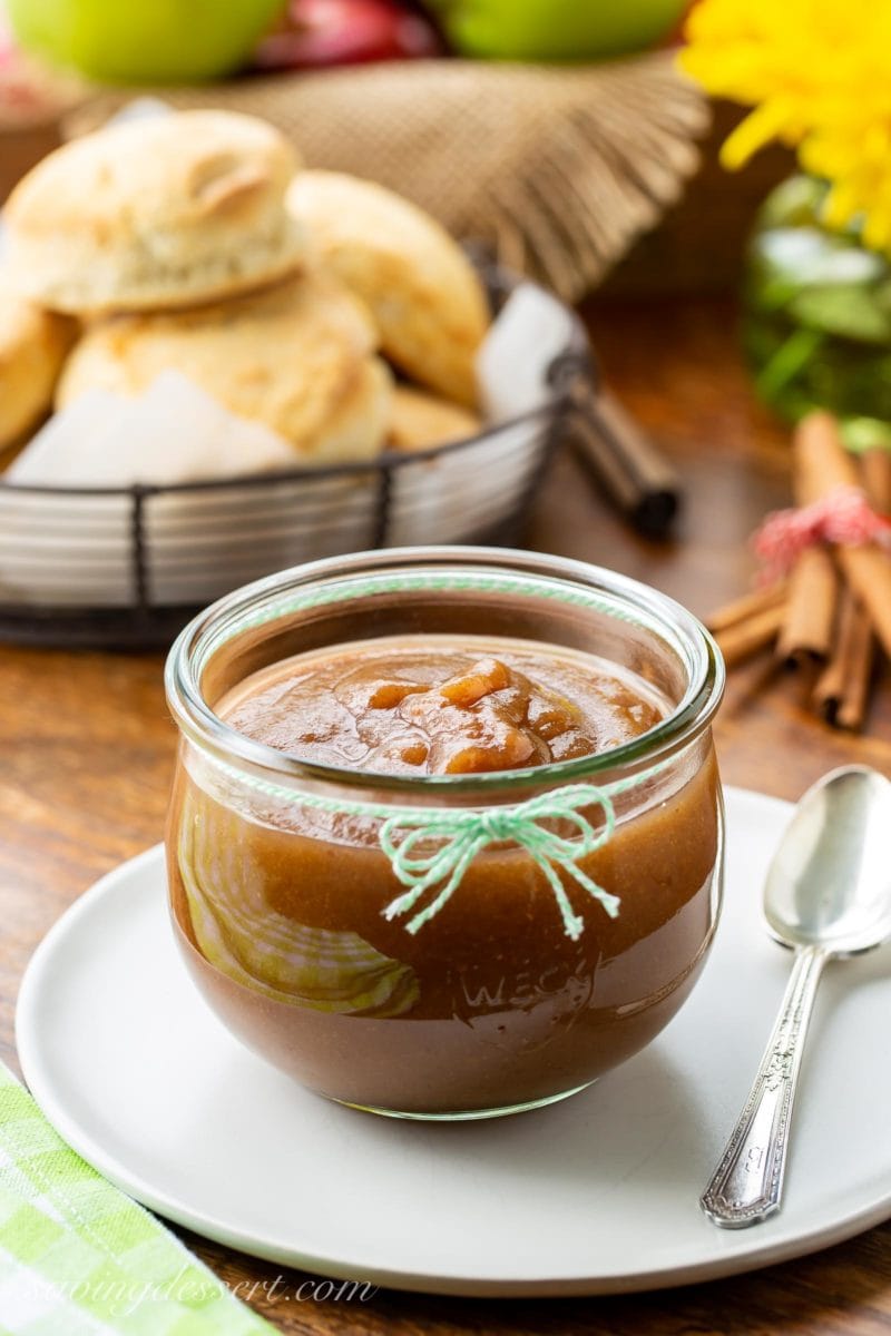 A large jar of homemade maple pear apple butter served with hot biscuits