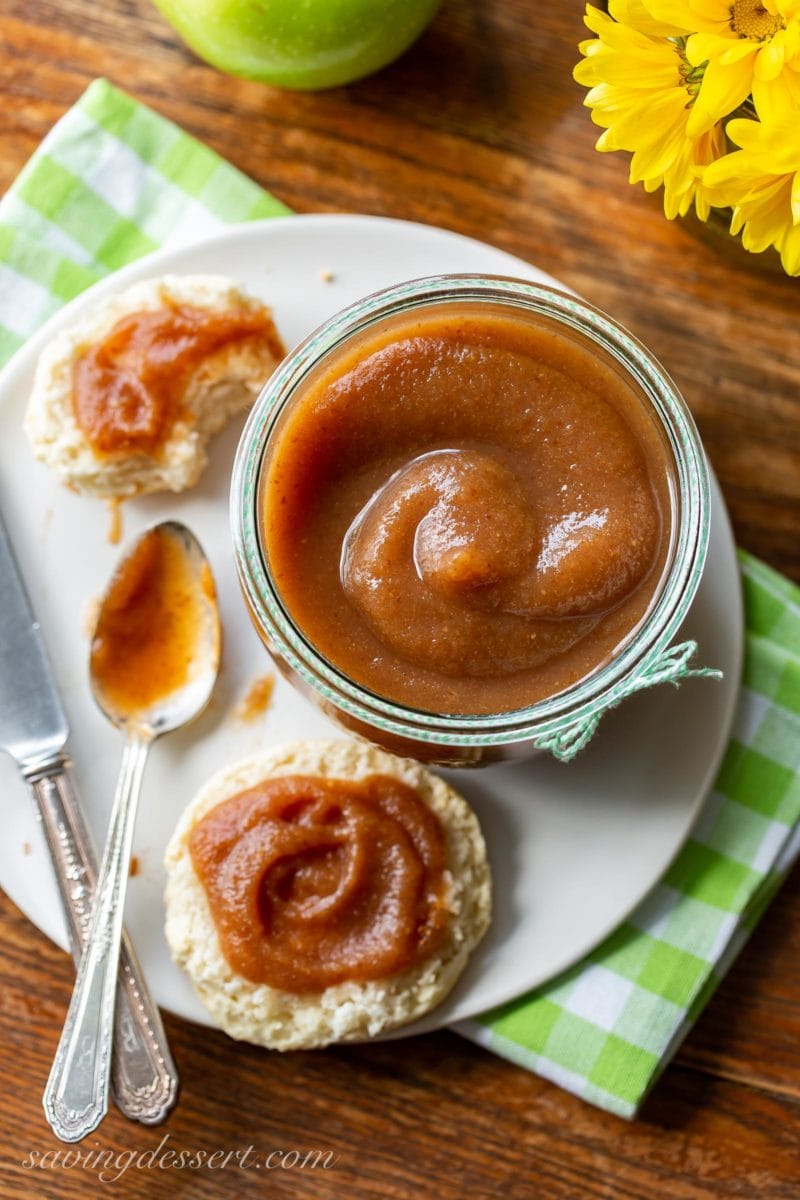 An overhead view of a big jar of homemade maple pear apple butter served with biscuits