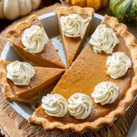 Sliced pumpkin pie decorated with whipped cream swirls