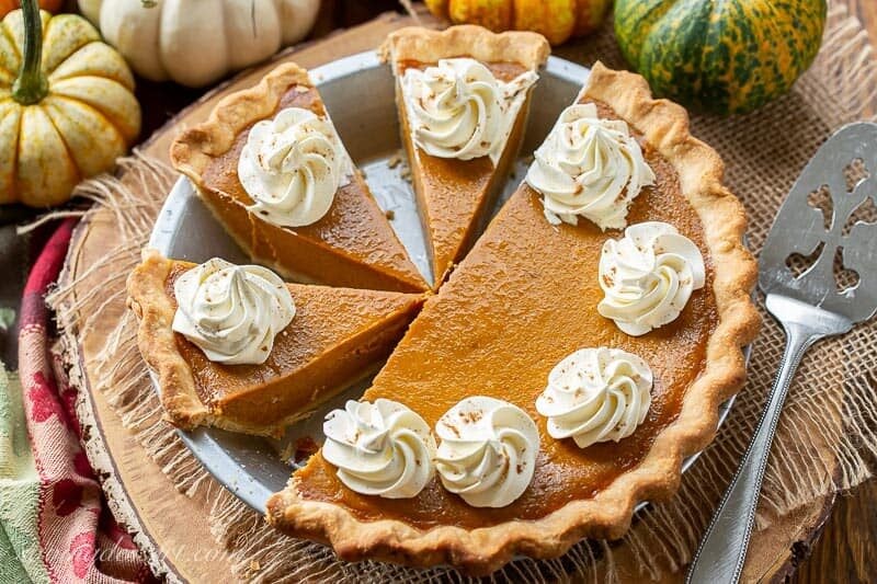 Sliced pumpkin pie decorated with whipped cream swirls