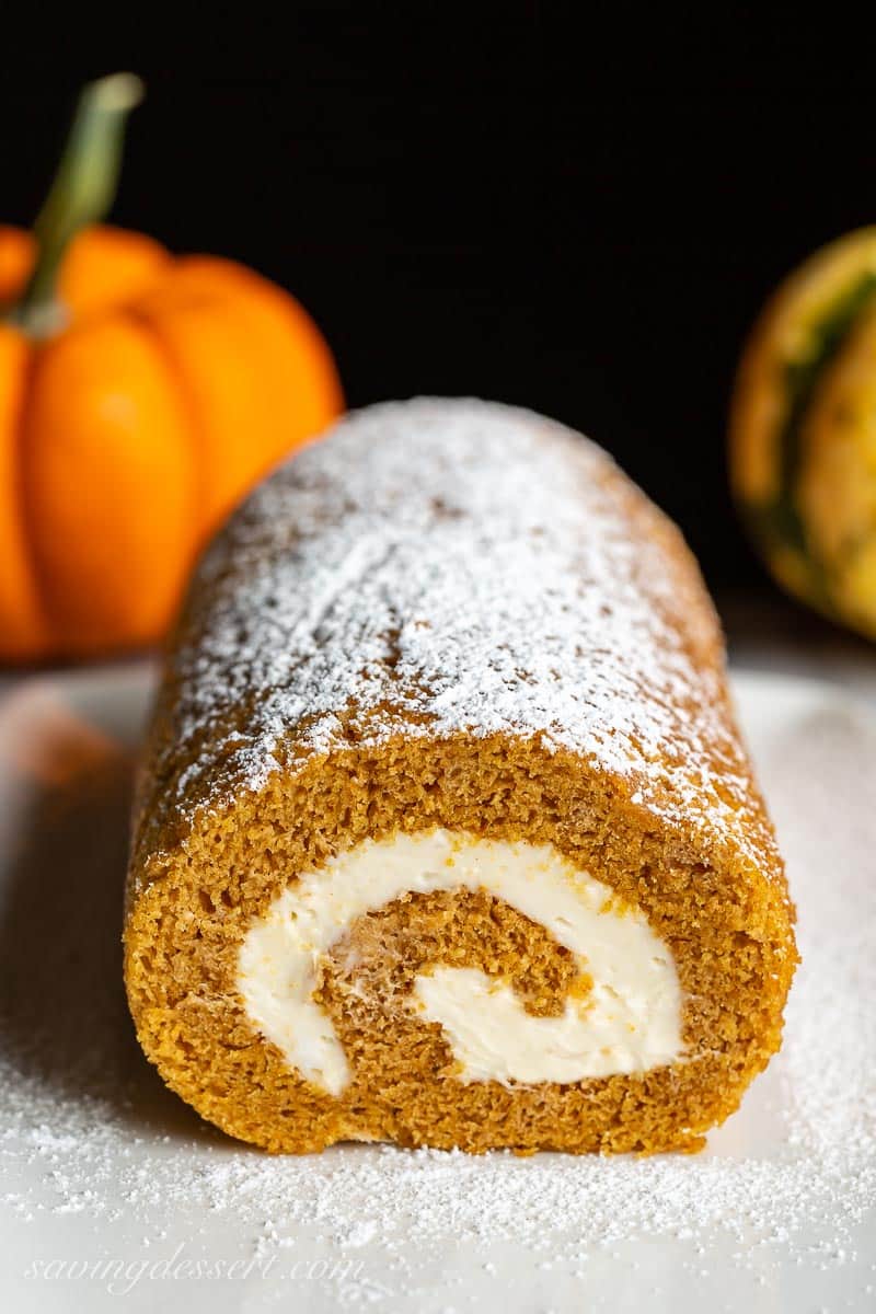 Closeup of a sliced pumpkin roll dusted with powdered sugar