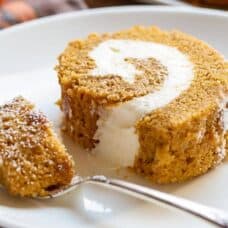 A closeup of a slice of pumpkin roll with a fork