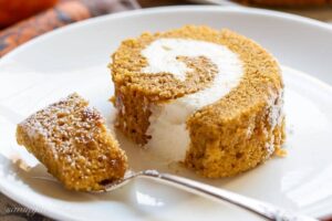 A closeup of a slice of pumpkin roll with a fork