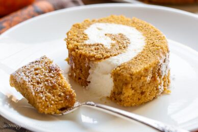 A closeup of a slice of pumpkin roll with a fork