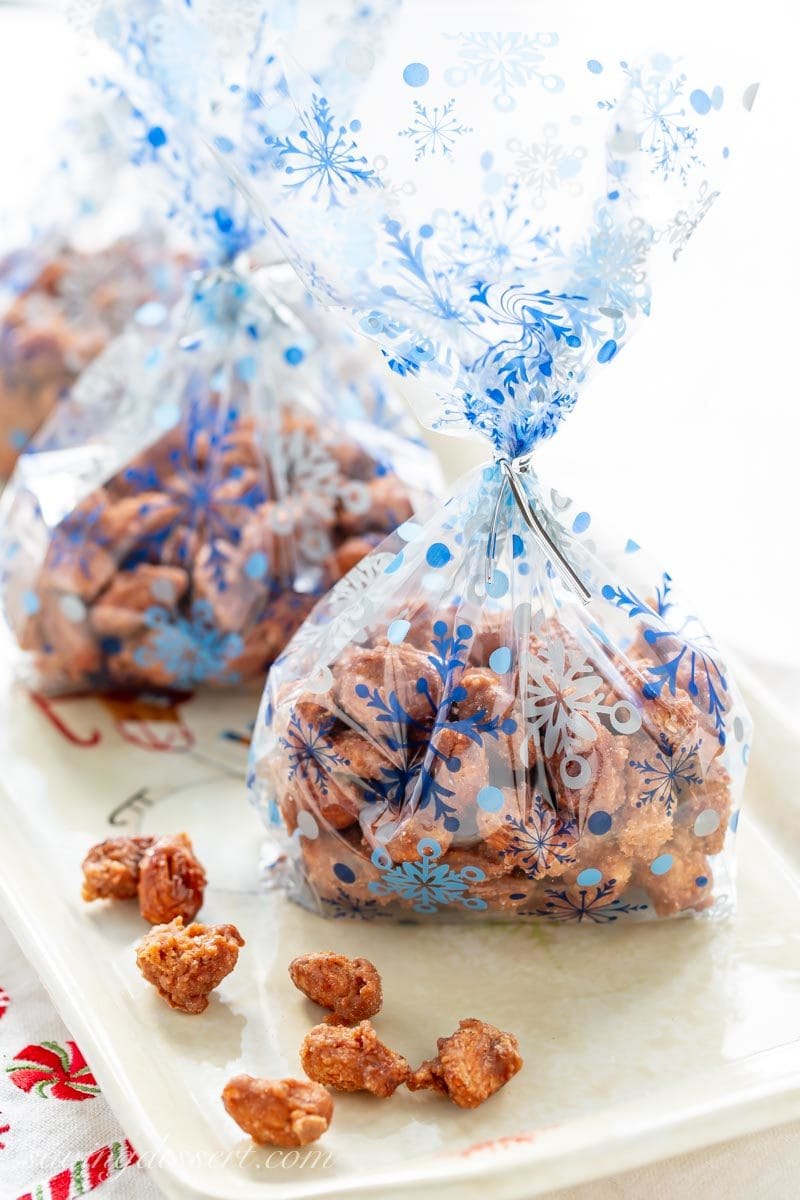 Burnt Sugar Almonds (Gebrannte Mandeln) - a traditional German recipe for delicious cinnamon sugar coated almonds like those you'll find in a Christkindlmarkt around the holidays. #savingroomfordessert #burntsugaralmonds #almonds #candiedalmonds #cinnamonalmonds #holidaygifts #ediblegifts #germanalmonds #gebranntemandeln a few clear holiday bags of burnt sugar cinnamon almonds ready for gifting