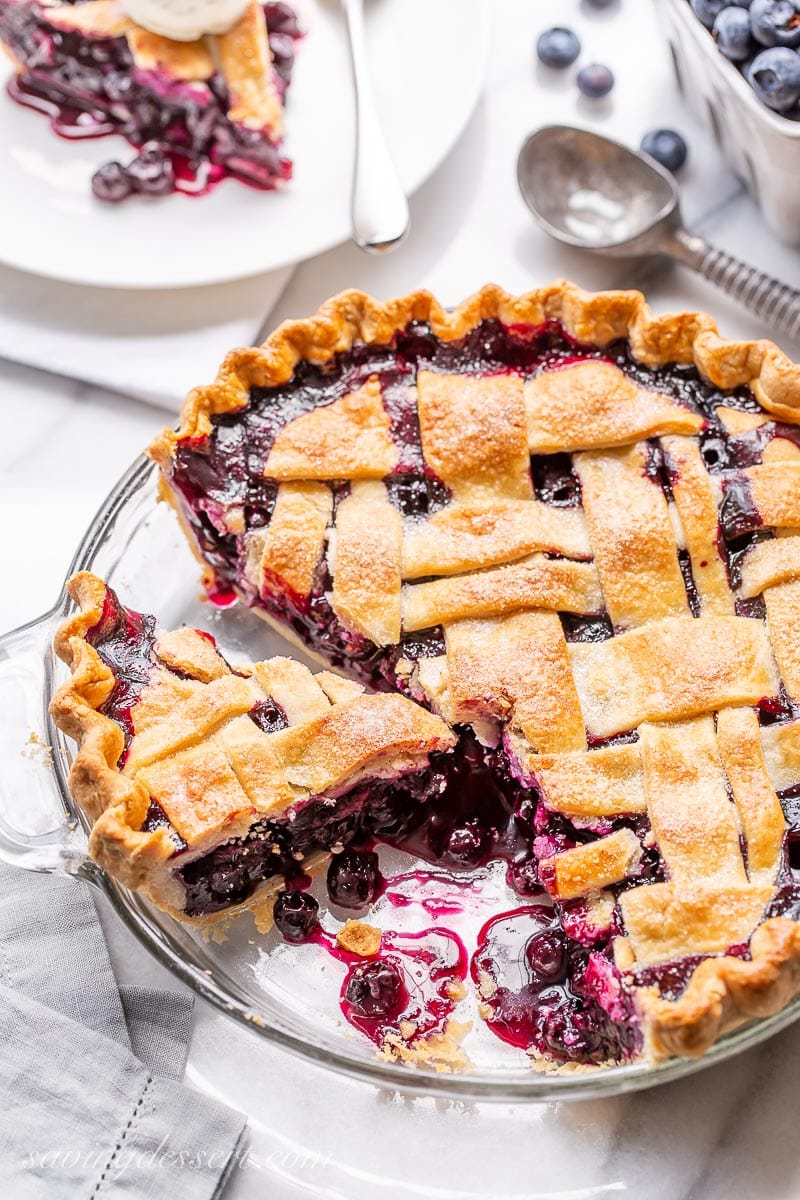 A sliced lattice topped blueberry pie with juicy blueberries in the pie plate