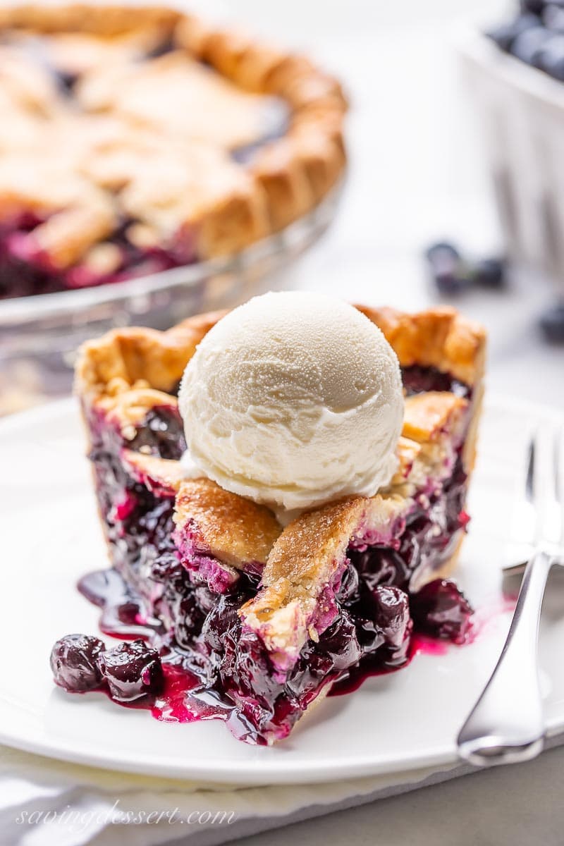 A slice of juicy blueberry pie topped with a scoop of vanilla ice cream