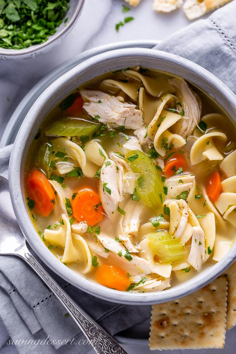 A bowl of soup with carrots, celery, chicken and onions