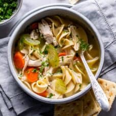 A bowl of chicken noodle soup served with crackers