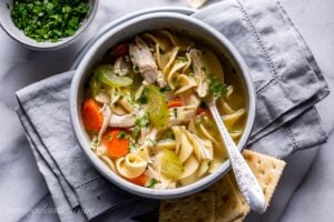 A bowl of chicken noodle soup served with crackers