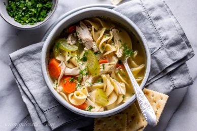 A bowl of chicken noodle soup served with crackers