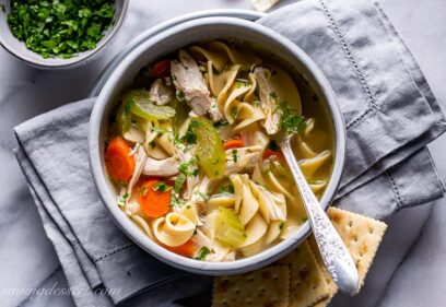 A bowl of chicken noodle soup served with crackers