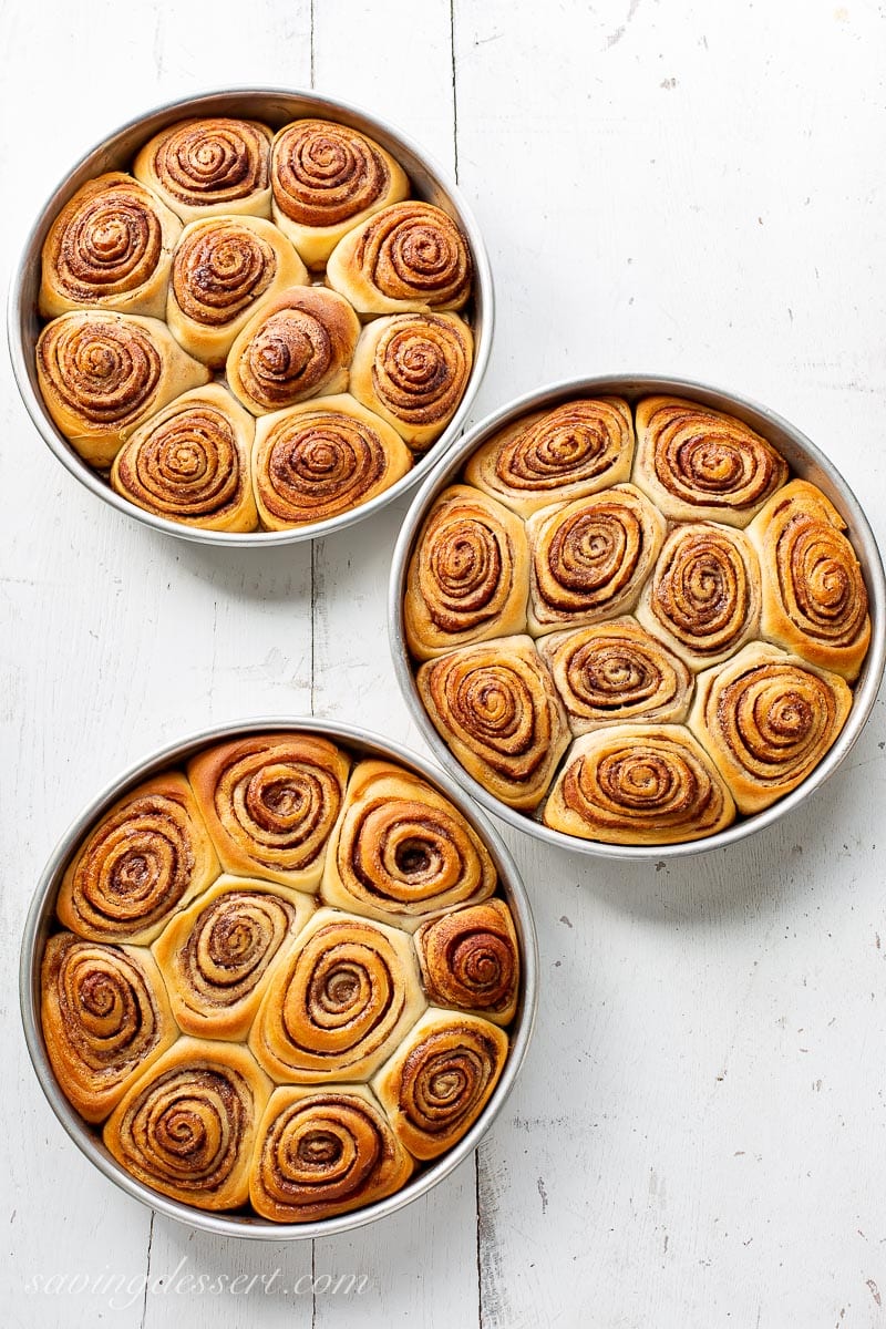 Three pans of fresh from the oven cinnamon rolls.
