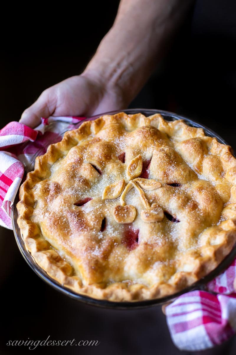 An overhead view of a hot from the oven cherry pie being held with two towels