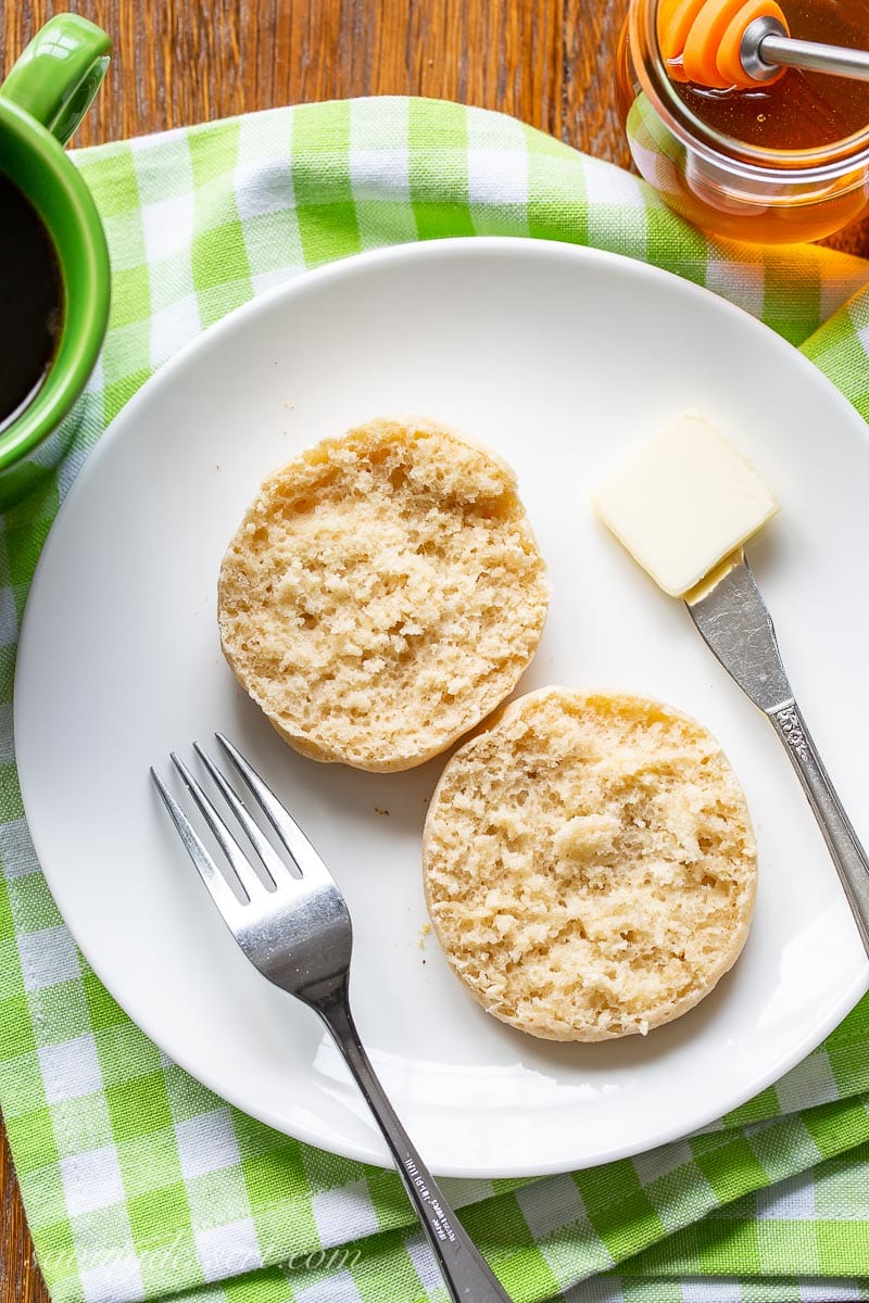 A split English muffin on a plate with butter