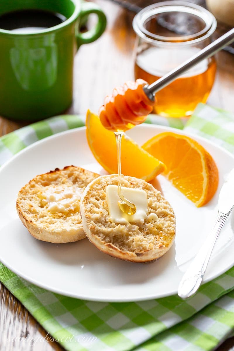 A split and toasted English muffin being drizzled with honey