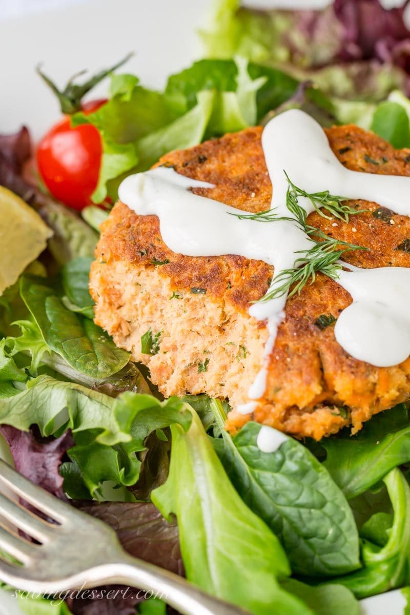 salmon patties with a drizzle of cucumber ranch dressing served over a green leafy salad