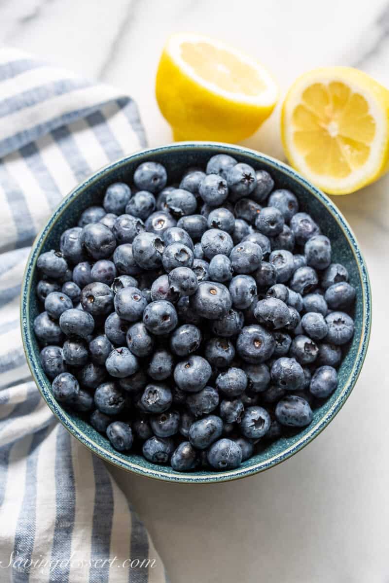 A bowl of blueberries with a sliced lemon on the side