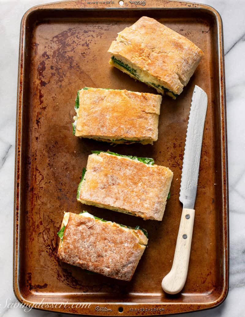 Four chicken pesto panini sandwiches ready to cook and press.