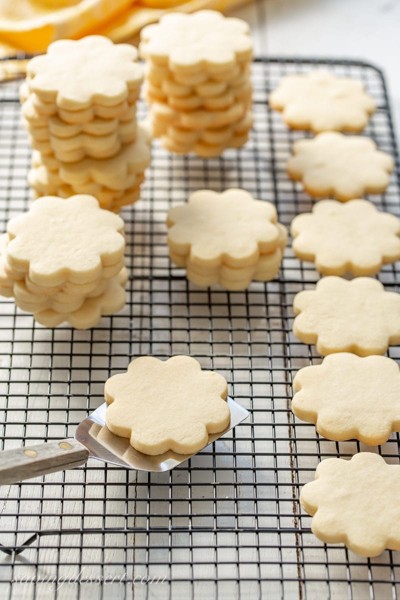 A cooling rack filled with flower shaped cut-out sugar cookies