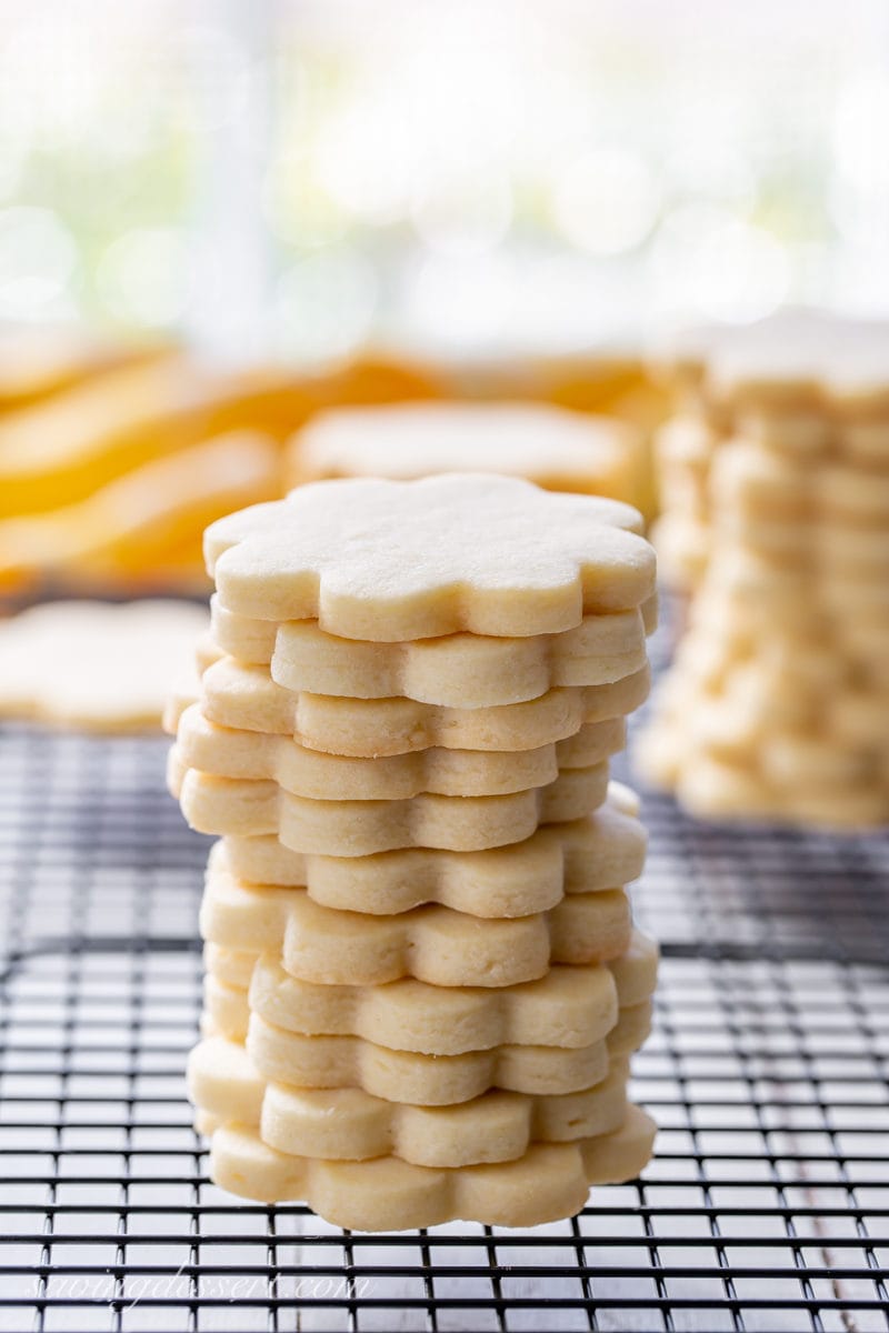 A stack of cut-out sugar cookies on a cooling rack