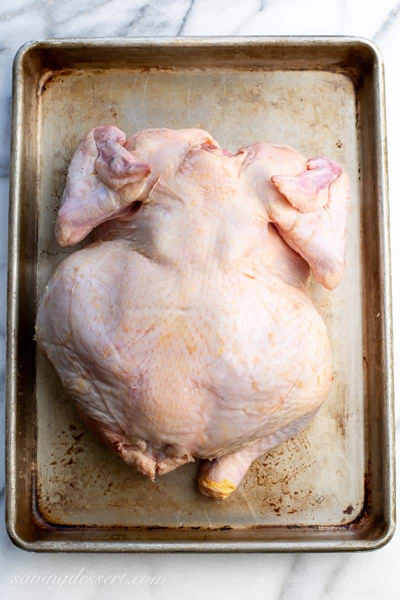 Overhead view of a whole upside down chicken on a baking sheet