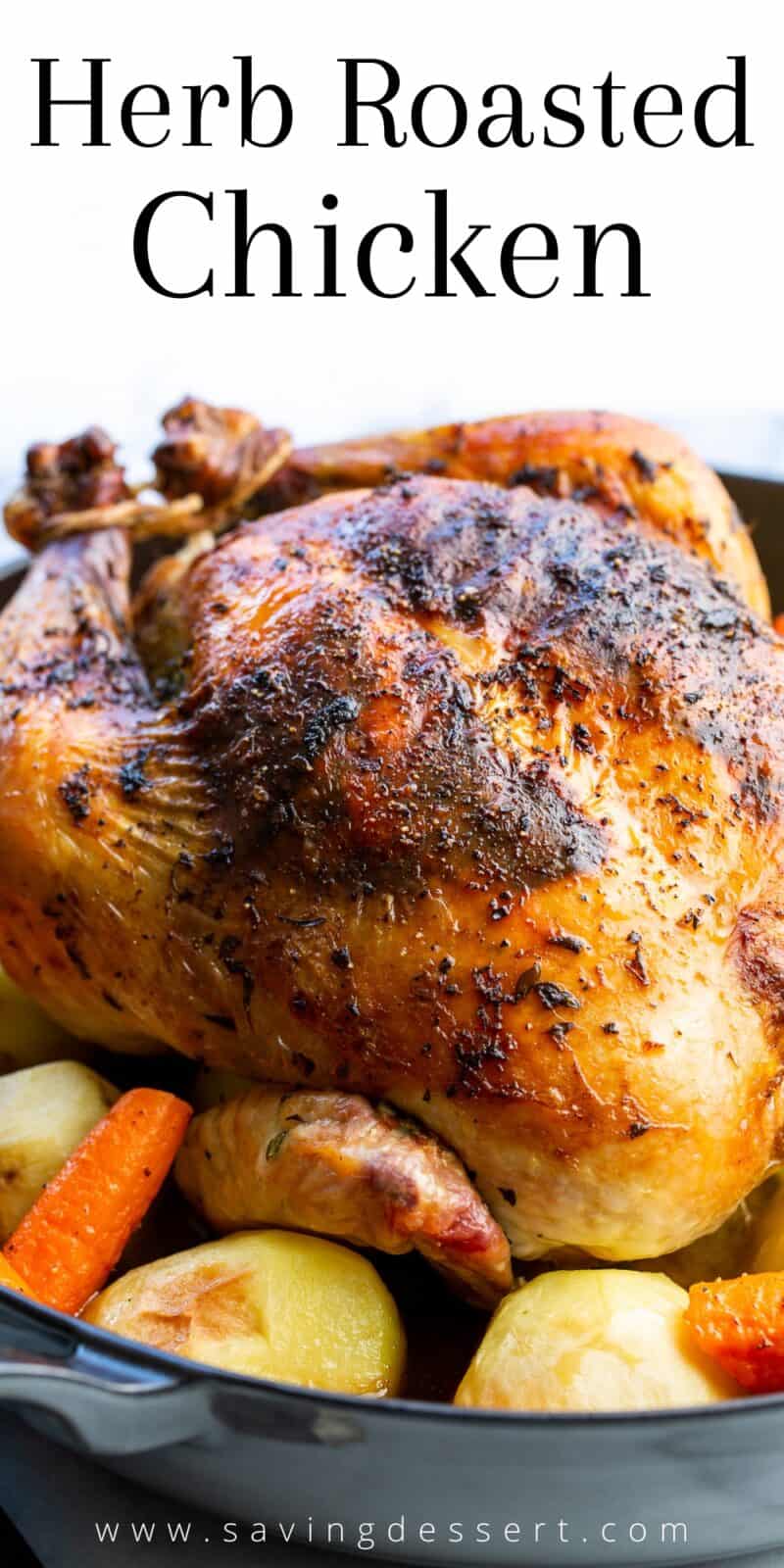 A closeup of a whole roasted chicken in a skillet with potatoes and carrots