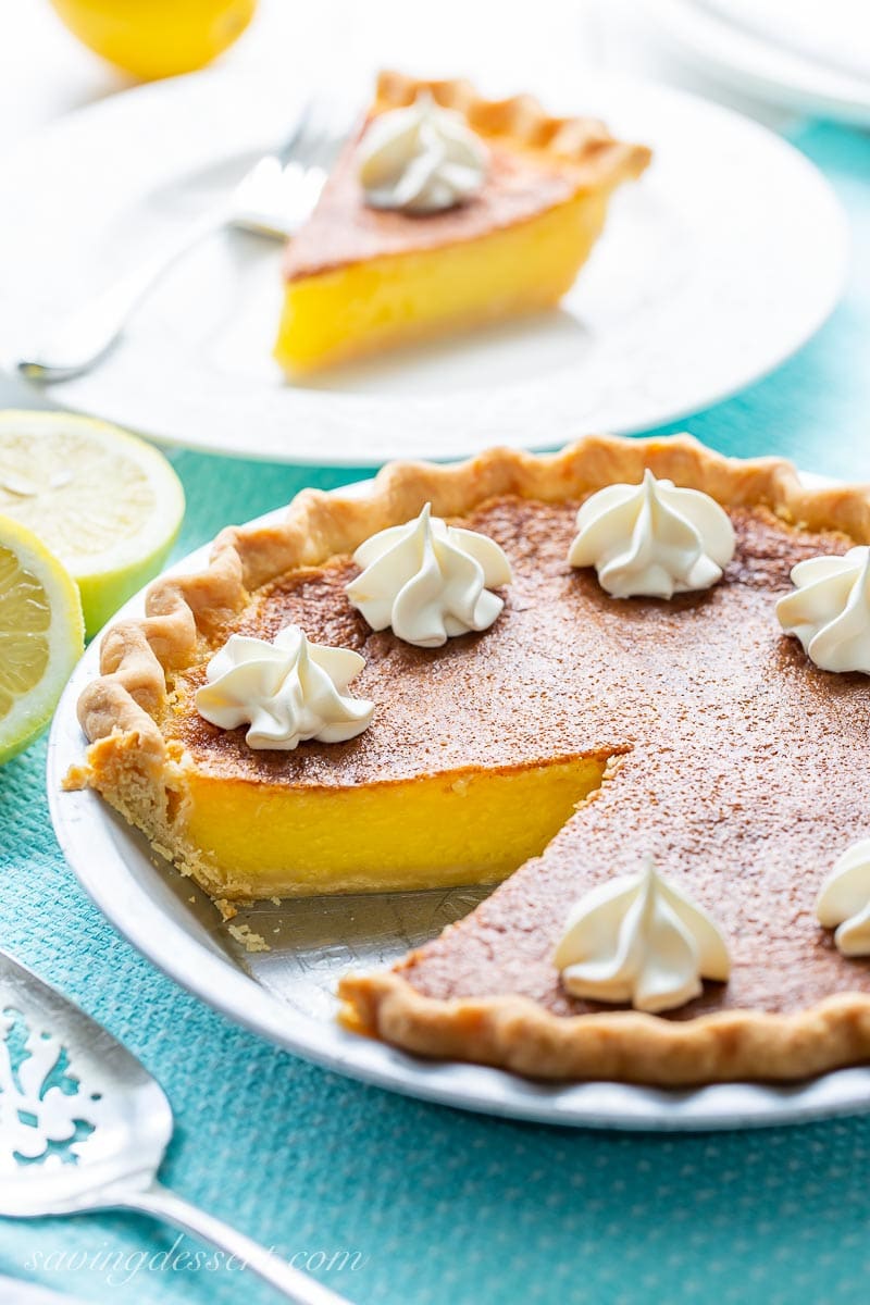 A sliced lemon pie with dollops of whipped cream on top