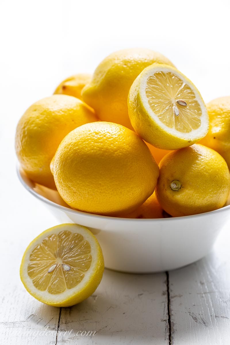 A bowl of fresh lemons with one sliced in half