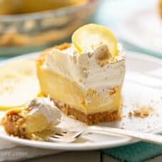 a partially eaten slice of lemon icebox pie on a plate with whipped cream and a lemon slice on top