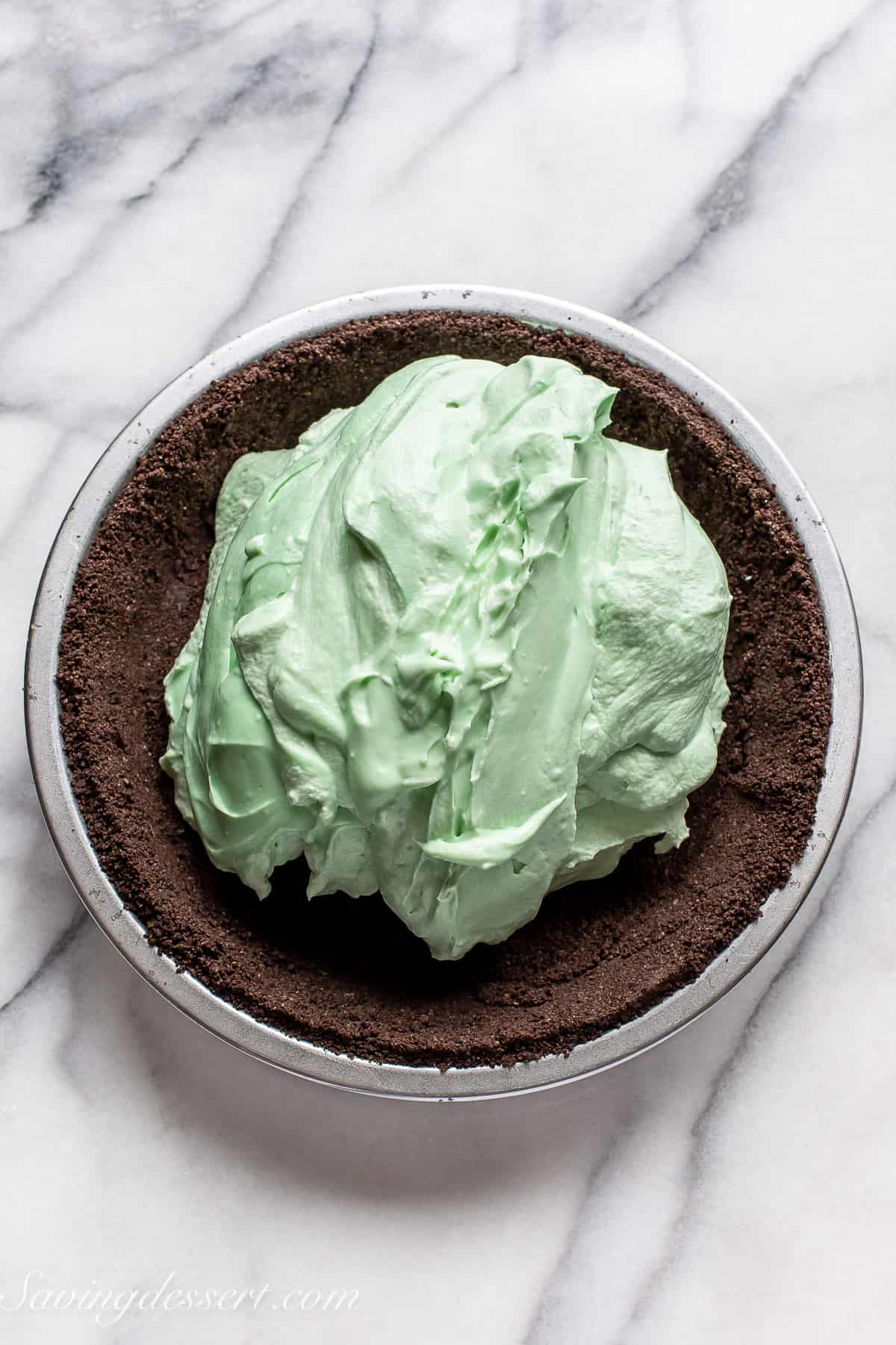 an overhead view of an oreo crust filling with mint green pie filling