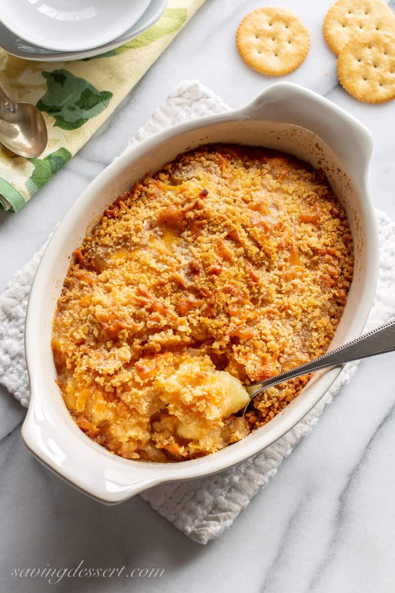 An overhead shot of a small casserole dish filled with baked pineapple casserole with crackers on top