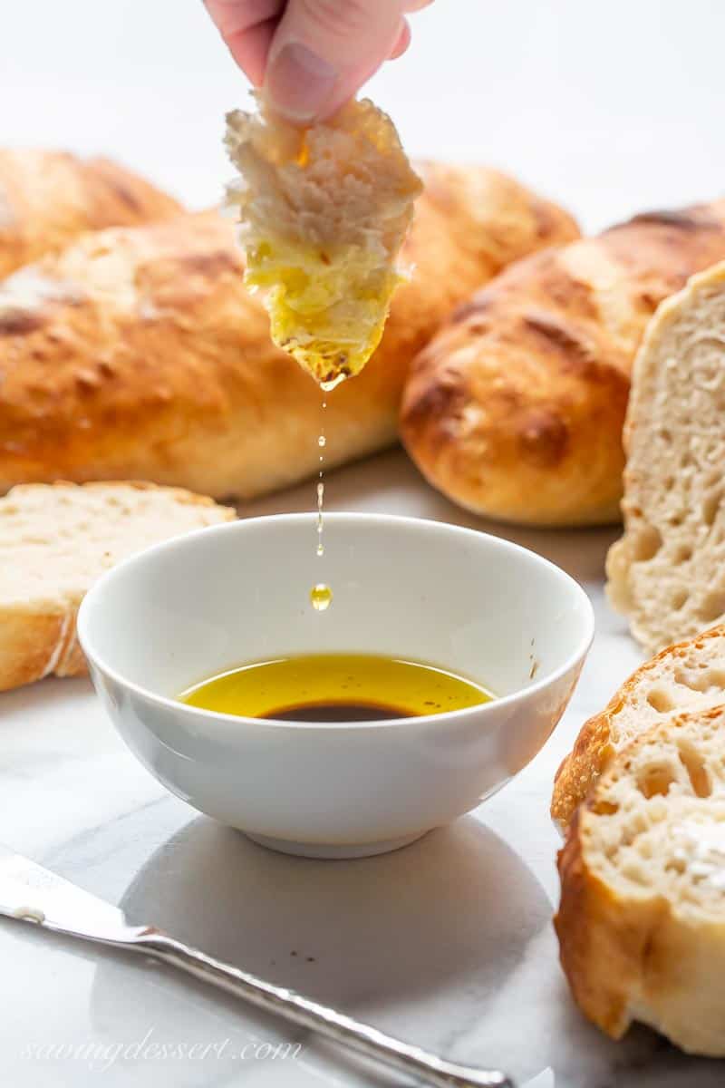 Fresh no-knead bread being dipped in a bowl of oil and balsamic vinegar