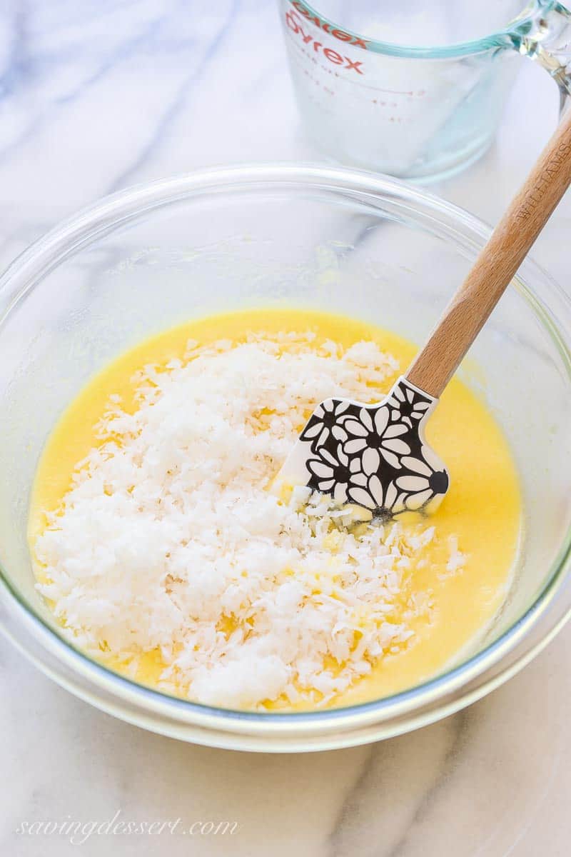 A bowl of pie filling with a cup of shredded coconut poured into the mix