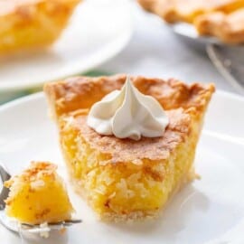 A slice of French coconut pie on a plate topped with whipped cream