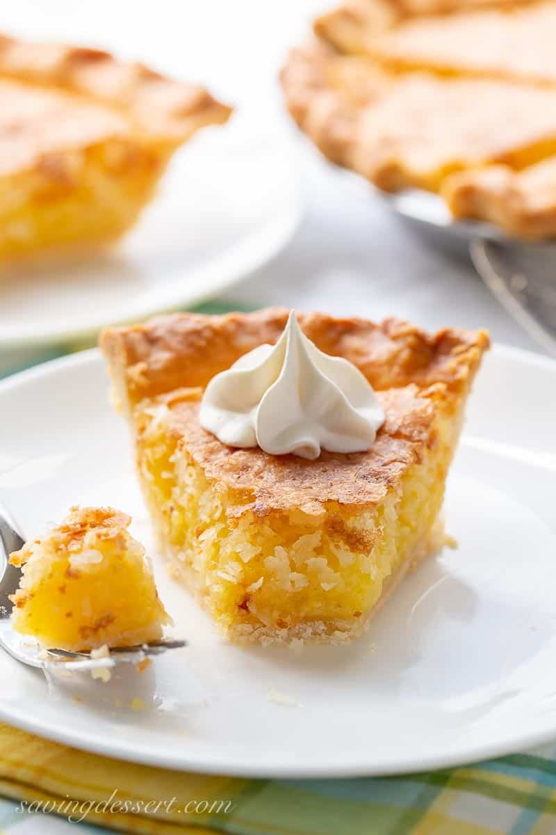 A slice of French coconut pie on a plate topped with whipped cream