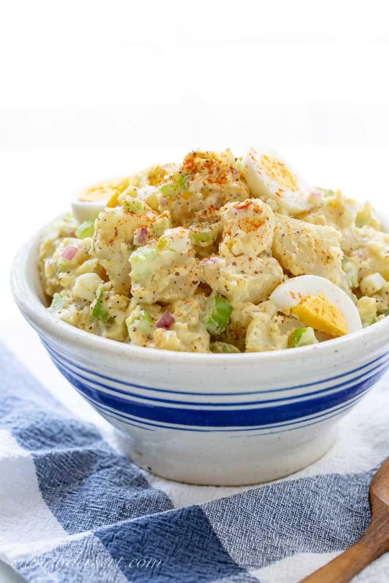 A bowl of creamy potato salad with hard cooked eggs on top