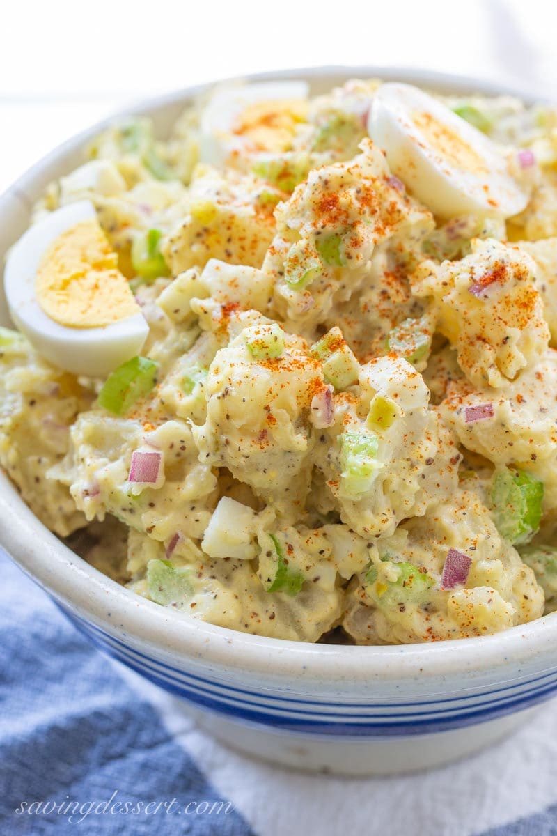 Bowl of creamy potato salad garnished with boiled eggs and paprika