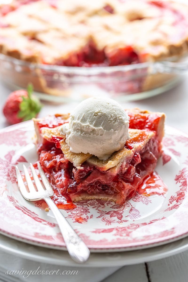 A slice of strawberry rhubarb pie with ice cream on top