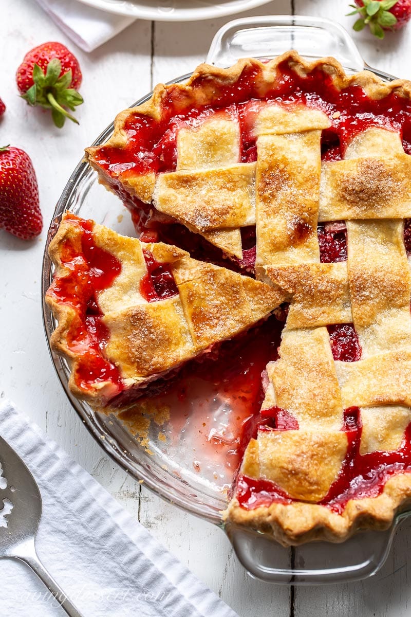 A sliced pie with a juicy red filling of strawberries and rhubarb topped with a lattice crust