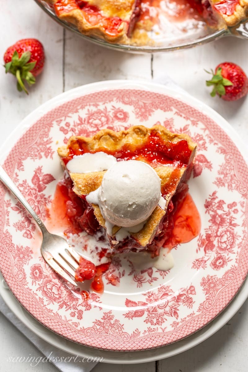 A piece of pie with ice cream on top with red juices on the plate