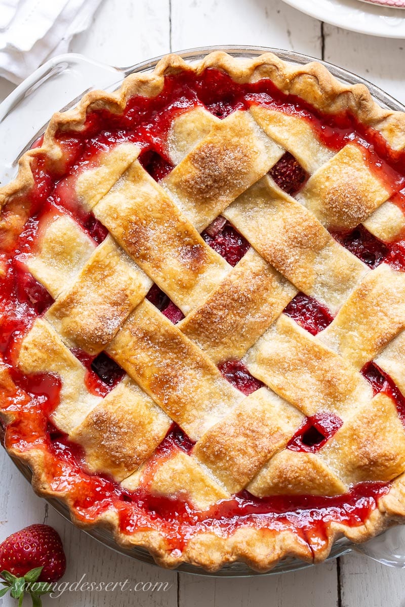 An closeup overhead view of a lattice topped strawberry rhubarb pie with red juices