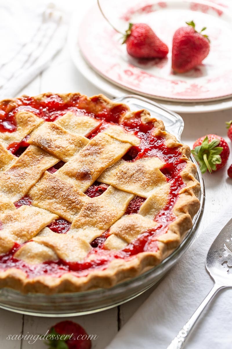 A strawberry rhubarb pie with a thick lattice crust with juices bubbling up between the crust