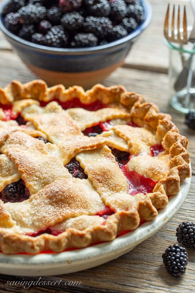 Homemade blackberry pie with a lattice crust served with fresh blackberries in a bowl