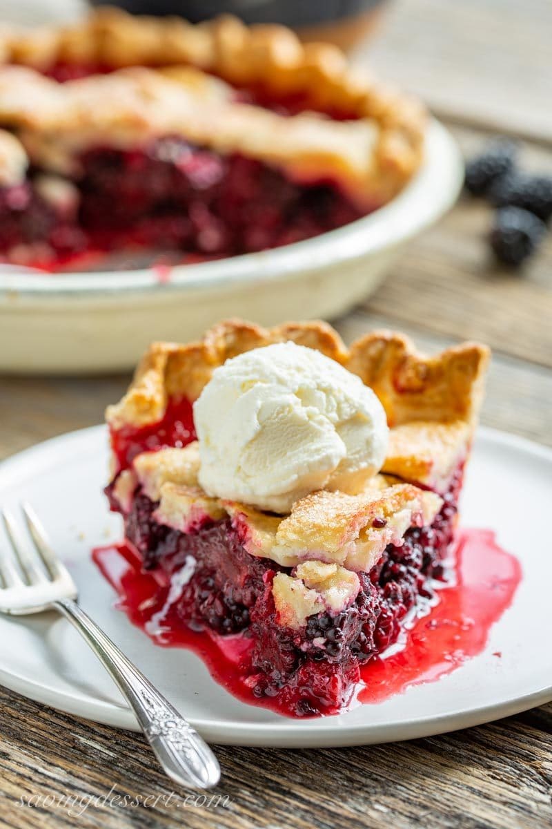 A slice of juicy blackberry pie with a scoop of ice cream