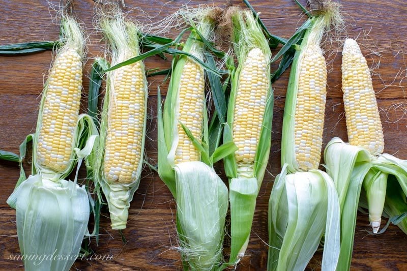 fresh summer ears of corn with husks and silk pulled down