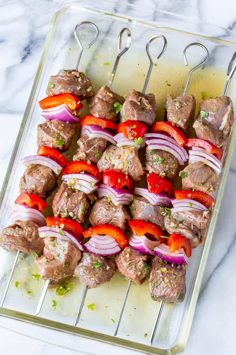 Marinated lamb skewers with red bell pepper and onion in a casserole dish