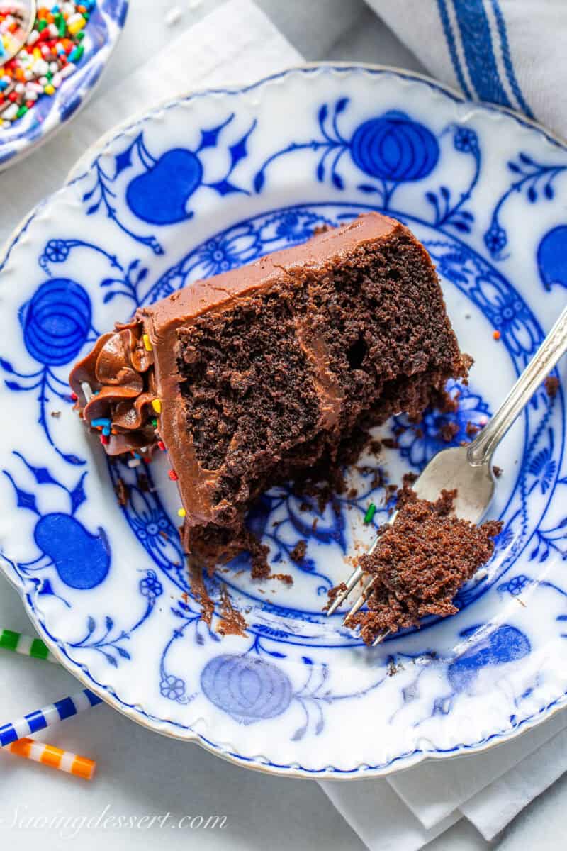 A partially eaten slice of chocolate cake on a blue plate.