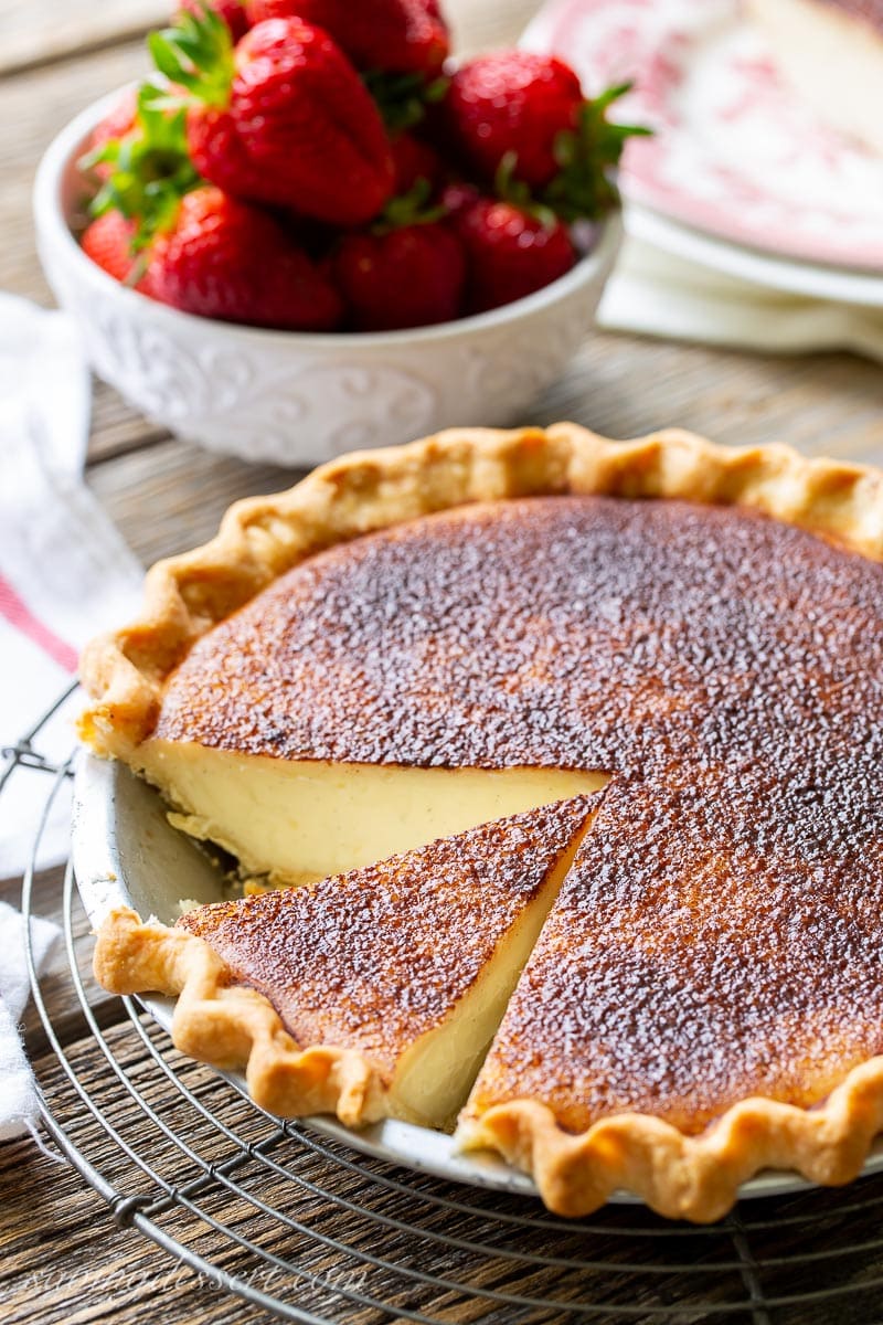 A sliced Hoosier Sugar Cream Pie served with fresh strawberries