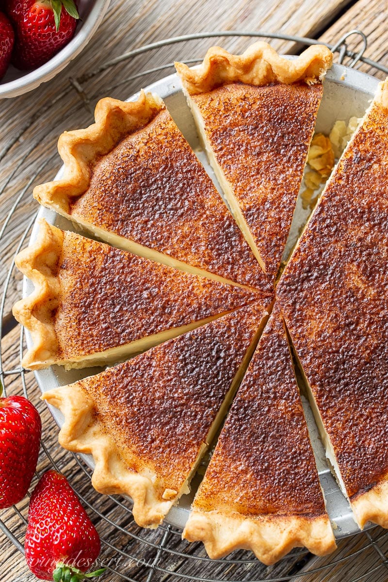 An overhead view of a sliced sugar cream pie with strawberries on the side